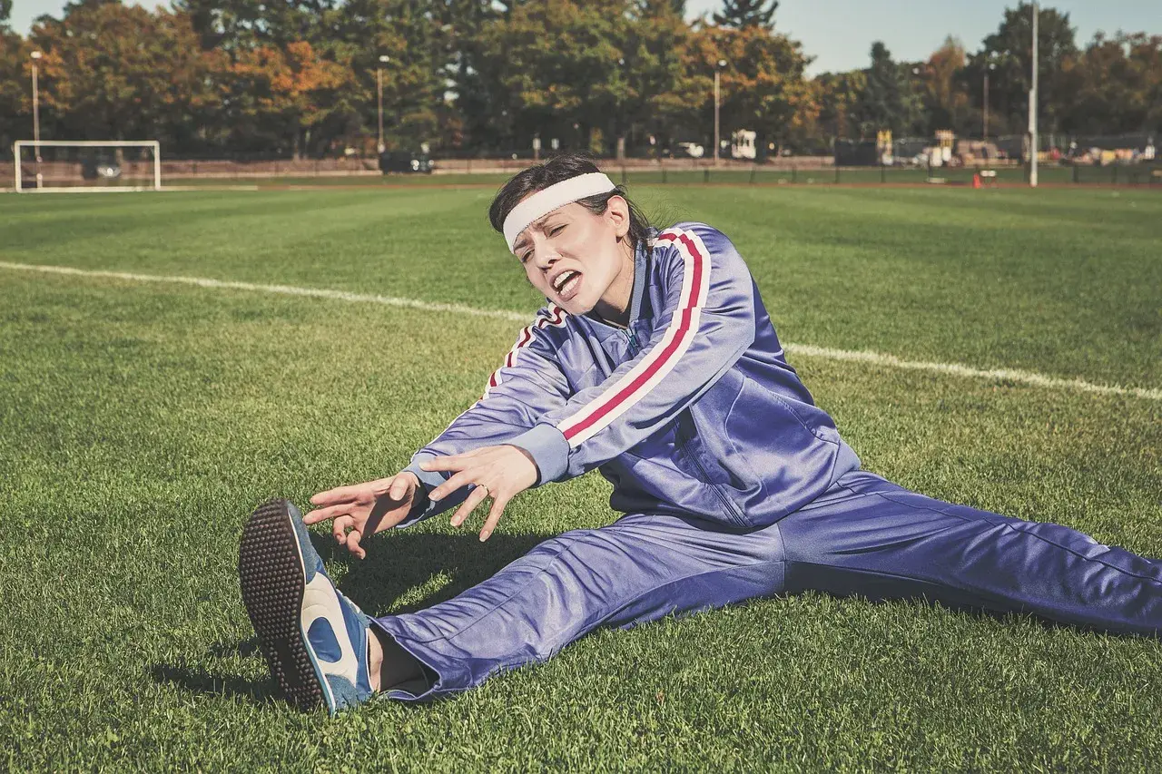 Athlete stretching outdoors on grass, representing the training and recovery routines that alcohol intake can subtly undermine