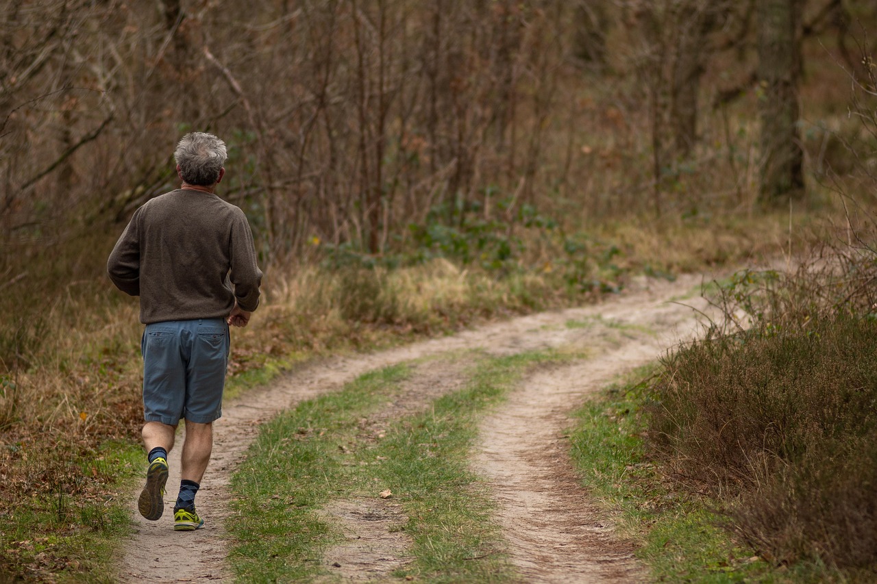 An older adult jogging along a forest trail as part of an active recovery routine