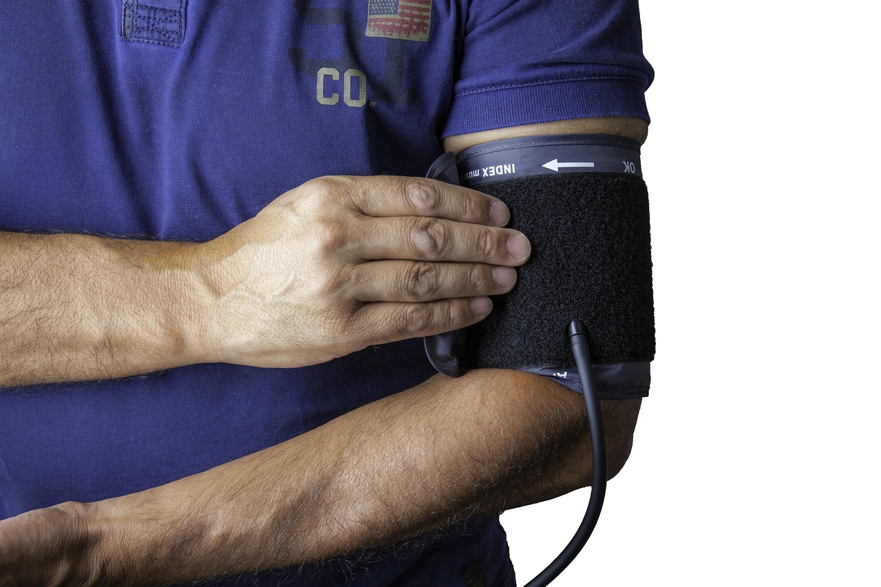 A doctor checking a patient’s blood pressure with a stethoscope and cuff during a clinical exam