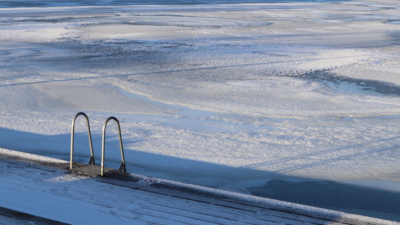 A frozen lake with a cleared opening for winter swimming, sunlight reflecting off the ice