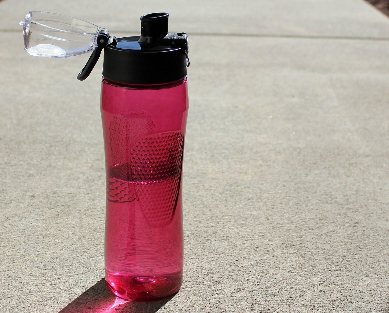A hand pouring water from a bottle, representing everyday fluid intake versus targeted electrolyte replacement