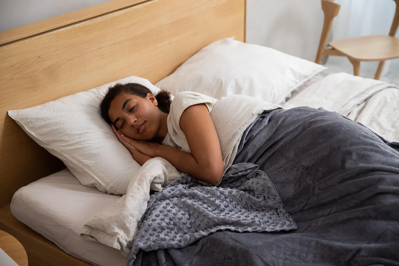 Woman, bed, blanket — illustrating Nutrition for Sleep: Carbs, Protein, and Timing